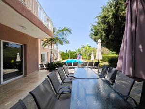 a long table with chairs and umbrellas on a patio at Villa Green Sea in Paphos