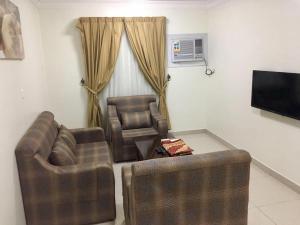 a living room with two chairs and a flat screen tv at Raha Suites in Dammam +11 photos