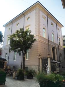 um grande edifício branco com uma árvore em frente em Hotel Europa Varese em Varese