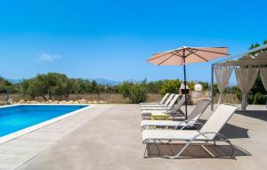 a group of lounge chairs and an umbrella next to a swimming pool at Can Paxaco in Alcudia