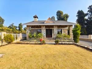 a house with a white fence and a yard at Basera by the Woods in Dehradun