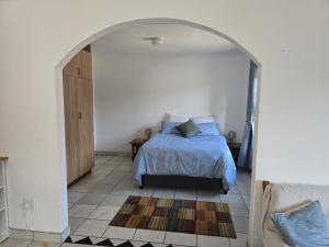 a bedroom with a bed and an arched doorway at Driftwood Haven in Mossel Bay