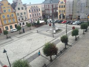 a woman walking through a city with a statue in a courtyard at Long Island in Grudziądz