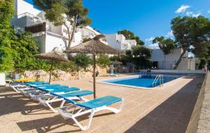 a group of lounge chairs and umbrellas next to a swimming pool at Playa D'or in Cala d´Or