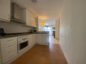 a kitchen with white cabinets and a tile floor at Riumar Solo Familias Serviplaya in Playa de Xeraco