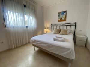 a bedroom with a bed with white sheets and a window at Riumar Solo Familias Serviplaya in Playa de Xeraco +40 photos