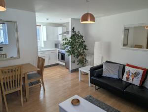a living room with a black couch and a table at Romeo's Retreat in Stratford-upon-Avon