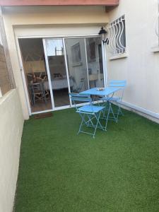 a table and chairs on a patio with green grass at La Parenthèse de Victoire in Aigues-Mortes