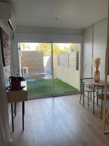 a living room with a sliding glass door with a table at La Parenthèse de Victoire in Aigues-Mortes