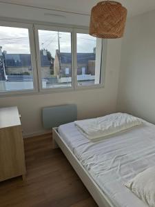 a bed in a room with two windows at Penvins in Sarzeau