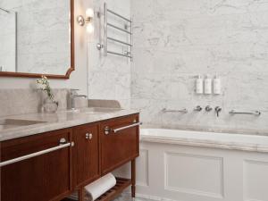 a bathroom with a sink and a tub and a mirror at Hotel Kämp in Helsinki +48 photos