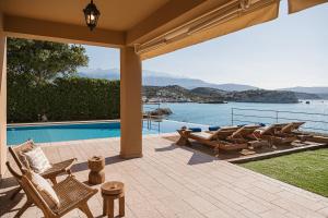 a patio with chairs and a view of the water at SK Place Luxury Seafront Villas Chania in Almyrida