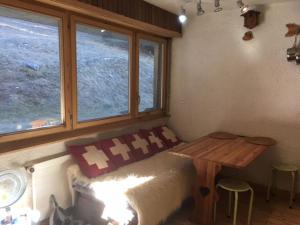 a room with a bed and a table and windows at Mountain Studio in La Tzoumaz