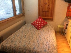 a small bed with a red pillow on it at Mountain Studio in La Tzoumaz
