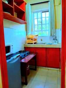 a kitchen with red cabinets and a stove and a window at Ladine Homestay - Ferrum Apartment in Eldoret