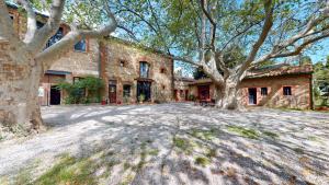 a large brick house with trees in front of it at Domaine du Mas Bazan in Alénya