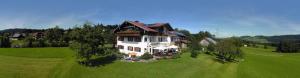 a large white house in a green field at Gästehaus Reichart in Scheidegg