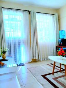 a living room with white curtains and a table at Ladine Homestay - Ferrum Apartment in Eldoret +2 photos
