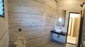 a bathroom with a wooden wall with a sink and a toilet at Mannat Bungalow in Amrāvati