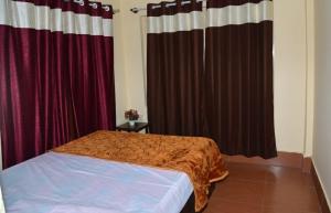 a bedroom with red curtains and a bed in a room at Joyful Homestay in Mysore
