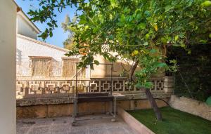 a bench next to a tree next to a wall at Es Baladre Beach in Alcudia