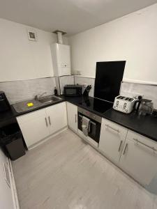 a kitchen with white cabinets and black counter tops at Horizon Hideaway in Swansea +3 photos