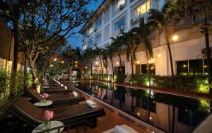a hotel with tables and chairs next to a pool at Harmony Indochine d'Angkor in Siem Reap