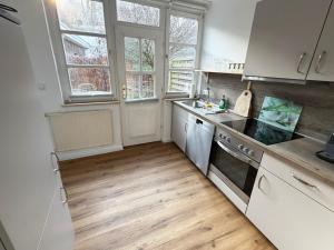 a kitchen with white cabinets and a wooden floor at Kalkberg Ferienwohnungen in Bad Segeberg