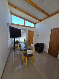 a living room with a table and chairs and a television at Alto La Florida Cabañas in Huasco