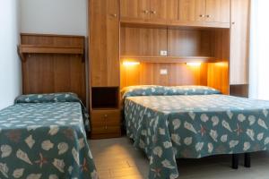 a hotel room with two beds and wooden cabinets at Hotel Jesolo Sand in Lido di Jesolo