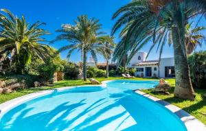 a swimming pool with palm trees in front of a house at Can Roca De Cala D'or in Cala d´Or