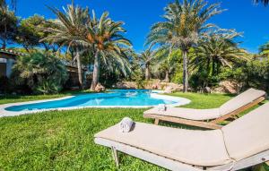 a pool with two lounge chairs and palm trees at Can Roca De Cala D'or in Cala d´Or