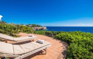a patio with two lounge chairs and the ocean at Can Roca De Cala D'or in Cala d´Or