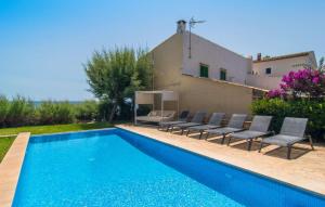a swimming pool with chairs and a house at Port Nou in Cala Bona