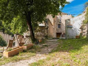 an old stone building with a tree and a chair at Casa espaiosa amb llar de foc in Ribes de Freser