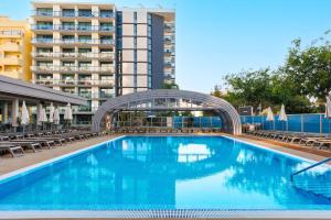 a swimming pool with chairs and a building in the background at Jupiter Algarve Hotel - Beach & Spa in Portimão