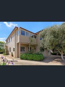 a large house with a tree in front of it at Beachside Apartment in Apollo Bay