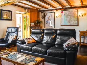 a living room with a leather couch and a table at Church House in Ulpha