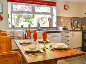 a kitchen with a wooden table with plates and utensils at Church House in Ulpha +21 photos