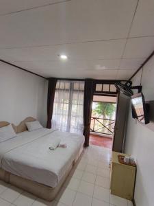 a bedroom with a bed and a tv and a window at Hotel Pandu Lakeside Tuktuk in Tuktuk Siadong