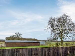 a barn and a tree behind a fence at Cleveland View Cottage in North Cowton