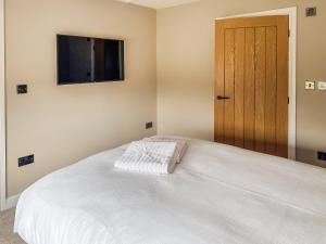 a bedroom with a white bed with a television on the wall at Cleveland View Cottage in North Cowton