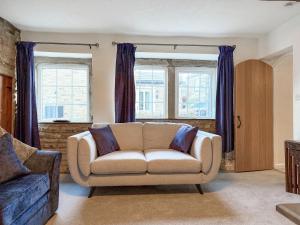 a living room with a couch and two windows at Wellhead Cottage in Haworth