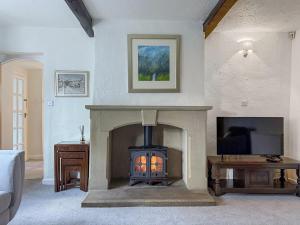 a living room with a fireplace and a tv at Wellhead Cottage in Haworth