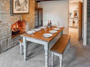 a table with plates and wine glasses and a fireplace at Wellhead Cottage in Haworth