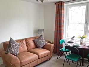 a living room with a brown couch and a table at Seasgair in Dingwall