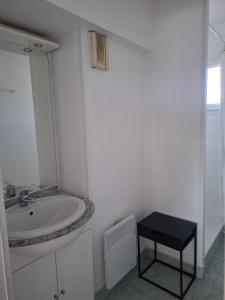 a white bathroom with a sink and a black stool at Appartement Riposa in Fréjus
