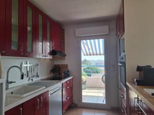 a kitchen with red cabinets and a door to a patio at Appartement Riposa in Fréjus +3 photos