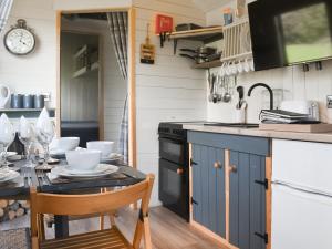 a kitchen with blue cabinets and a table with chairs at Shepherds Hut - Uk50043 in Chipping