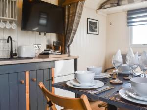 a kitchen with a table with plates and wine glasses at Shepherds Hut - Uk50043 in Chipping